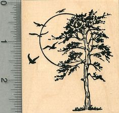 a rubber stamp with a tree and two birds flying in the sky, on top of a ruler