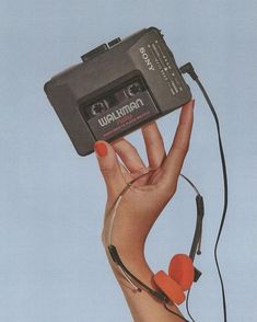 a woman holding up an old camera with headphones attached to it's sides