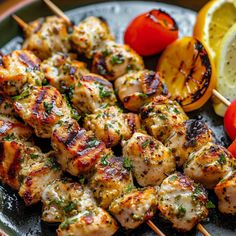 chicken kabobs on skewers with tomatoes and lemon wedges