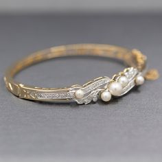 This stunning bracelet is a perfect period piece in exquisite condition. The bracelet features a bangle design with a hinged opening at the side. The top of the bracelet is encrusted with diamonds and pearls. The pearls and cultured and measure 6.14mm (largest and 3.84 (smallest). The design features single cut round diamonds, thirty two of them. The stones are VS/SI clarity and are G/H color. They measure 1.5mm each for a total weight of 0.48cttw. The piece is constructed in solid 14k yellow go Bangle Design, Period Piece, Diamond Bangles, Diamond Bangle Bracelet, Diamonds And Pearls, Thirty Two, Diamond Bangles Bracelet, Bangle Designs, Diamond Bangle