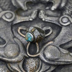 Central Asian Seljuk Style Afghan Turkmen Silver Ring with Brass Gilding and Persian Turquoise Gemstone The Sälçük (Seljuk) Dynasty (Türki: سَلجُك; Farsi: سلجوق) was a dynasty of Oğuz (Oghuz) Türkmän (Turkmen) origin, founded by members of the Qınıq sub-tribe in the Early Middle Ages. Persian jewelry revolutionized under their rule and many molds, particularly those for rings, were passed down to modern Afghani and Turkmen artisans, who used them to recast these rings in silver with gold or brass gilding. Essentially, these rings were vintage reproductions of medieval Sälçük pieces. However, there are also cases where these Afghani and Turkmen artisans developed their own derivative styles, mixing elements of original Sälçük jewelry. The two types of jewelry are often difficult to tell Bohemian Engraved Turquoise Ring For Gift, Engraved Bohemian Turquoise Ring, Engraved Turquoise Rings As Gift, Traditional Turquoise Rings Collectible, Traditional Oval Turquoise Ring, Traditional Turquoise Inlay Ring, Traditional Handmade Silver Turquoise Ring, Traditional Turquoise Cabochon Jewelry, Traditional Natural Stone Ring Jewelry