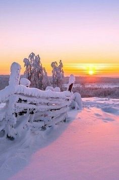 the sun is setting over a snowy field