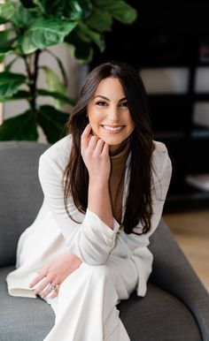 a woman sitting on top of a couch next to a plant