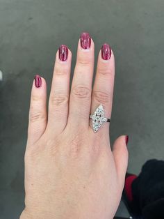 a woman's hand with a diamond ring on her finger and red nail polish