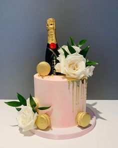 a pink cake with white flowers and a bottle of champagne