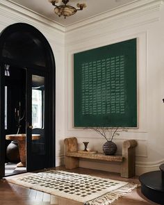 a room with a large chalkboard on the wall next to a bench and rug