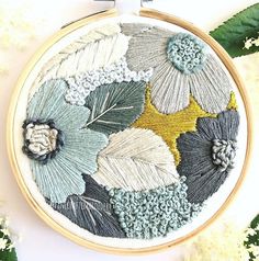 a close up of a embroidery on a hoop with flowers and leaves in it,