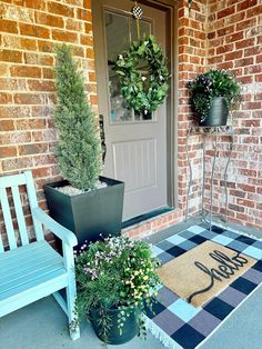 two potted plants sitting on the front porch next to a blue bench and door