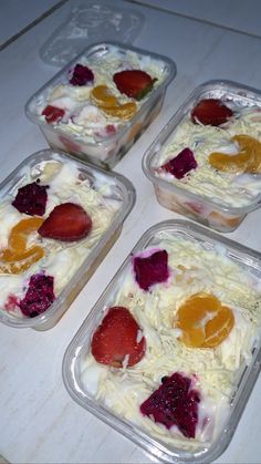 four plastic containers filled with fruit on top of a white counter next to each other