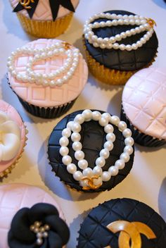 cupcakes decorated with black, white and pink icing are arranged on a table