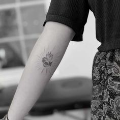 a woman's arm with a small sunflower tattoo on the left inner forearm