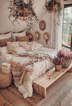 a bed sitting in a bedroom next to a window with lots of pillows and blankets on top of it