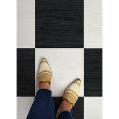 a person standing on a checkered black and white floor with their feet propped up