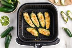 an air fryer with zucchini and other vegetables on the counter next to it