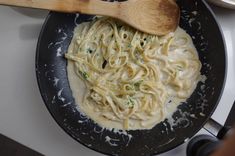 a skillet with some noodles and a wooden spoon