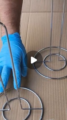 a person wearing blue gloves is cutting through some metal circles on a cardboard box with scissors