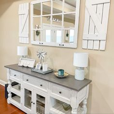 a white table topped with a mirror next to a lamp and a wall mounted mirror