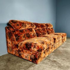 an orange couch sitting on top of a carpeted floor next to a blue wall