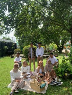 a group of people sitting on top of a lush green field next to each other