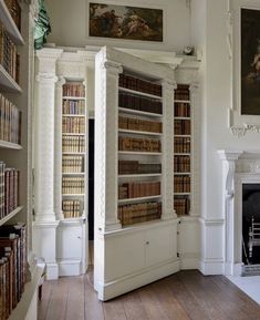 a room filled with lots of books on top of white bookcases next to a fire place