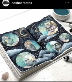 an open book with pictures of the moon and stars on it, sitting next to a cup of coffee