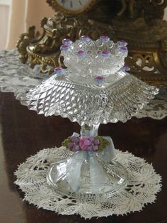 two glass dishes sitting on top of a wooden table next to a gold framed clock