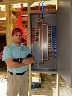 a man standing in front of an electrical panel with red and blue wires attached to it