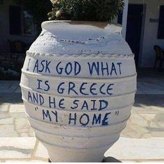 a large white vase with writing on it and a potted plant in the middle that says, i ask god what is greece and he said my home