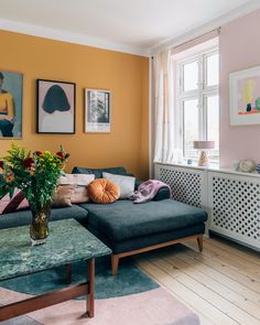 a living room filled with furniture and paintings on the wall above it's windows