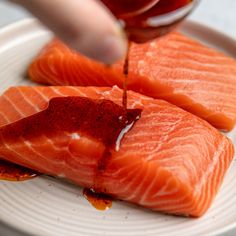 two pieces of salmon being drizzled with sauce