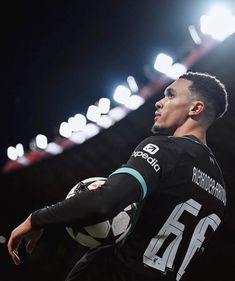 a man holding a soccer ball in his right hand and looking up at the sky