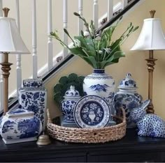 blue and white vases on a black table with lamps in front of the banister