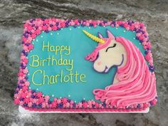 a birthday cake with pink frosting and a unicorn on the top, sitting on a table