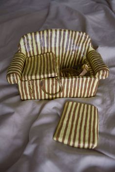 a brown and white striped bag sitting on top of a bed next to a pillow