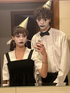 two people dressed up in costumes standing next to each other and one holding a cell phone