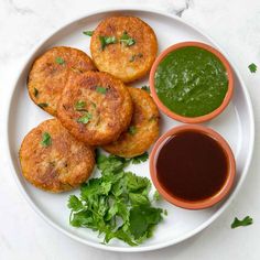 some food is on a white plate with sauces and green garnishes