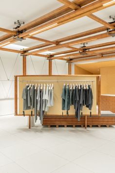 an empty room with clothes hanging on racks and wooden slats in the ceiling,