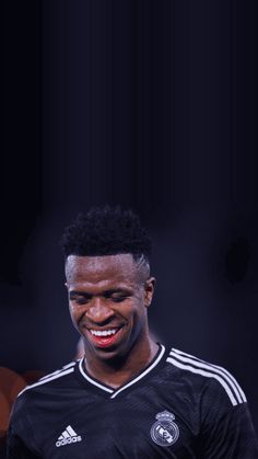 a man in a black jersey smiling at the camera with his hands on his hips