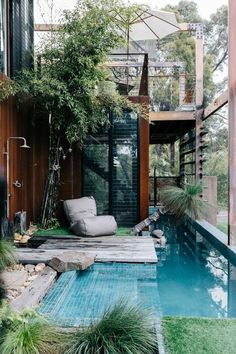 an outdoor living area with a pool and lounge chair in the foreground, surrounded by greenery