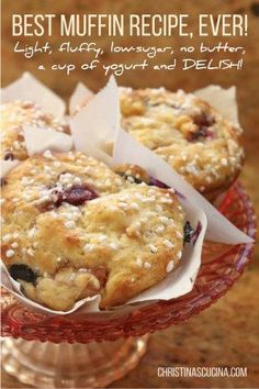 two muffins sitting on top of a red glass cake plate with napkins