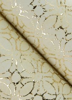 a white and gold textured surface with black spots