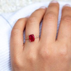 a woman's hand with a ring on it and a red stone in the middle