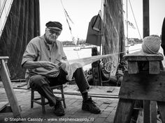 an old man sitting on a chair next to a boat