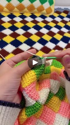 a person is knitting on a colorful blanket