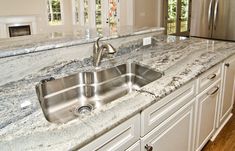 a kitchen with marble counter tops and stainless steel appliances in the middle of the room