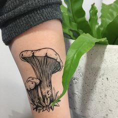 a woman's leg with a tattoo of a mushroom and leaves on the side