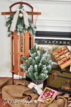 a small christmas tree sitting on top of a pile of burlocks next to an old suitcase