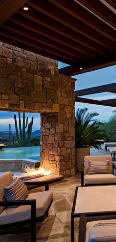 an outdoor living area with couches and tables next to a fire pit at dusk