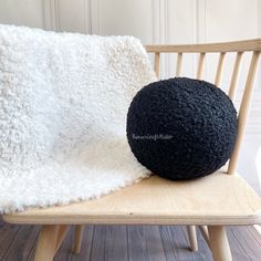 a black ball sitting on top of a wooden chair