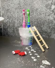 two toothbrushes sitting on top of a plastic cup next to a wooden ladder